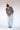 Person im anthrazitfarbenen Whisper of Inspiration Polo mit langen Ärmeln und heller Jeans in lockerer Pose vor hellem Studiohintergrund.